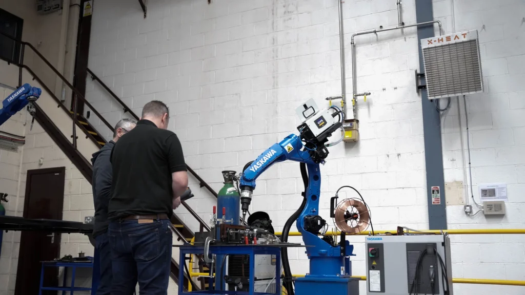two workers drilling something with an industrial drill with a x-heat nano-heater high on the wall above them.