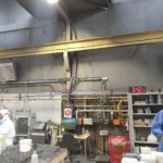 two workers standing underneath two separate x-heat nano-heaters, neither of them are turned on.