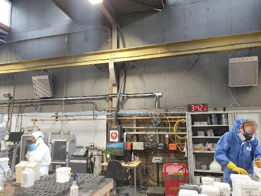 two workers standing underneath two separate x-heat nano-heaters, neither of them are turned on.