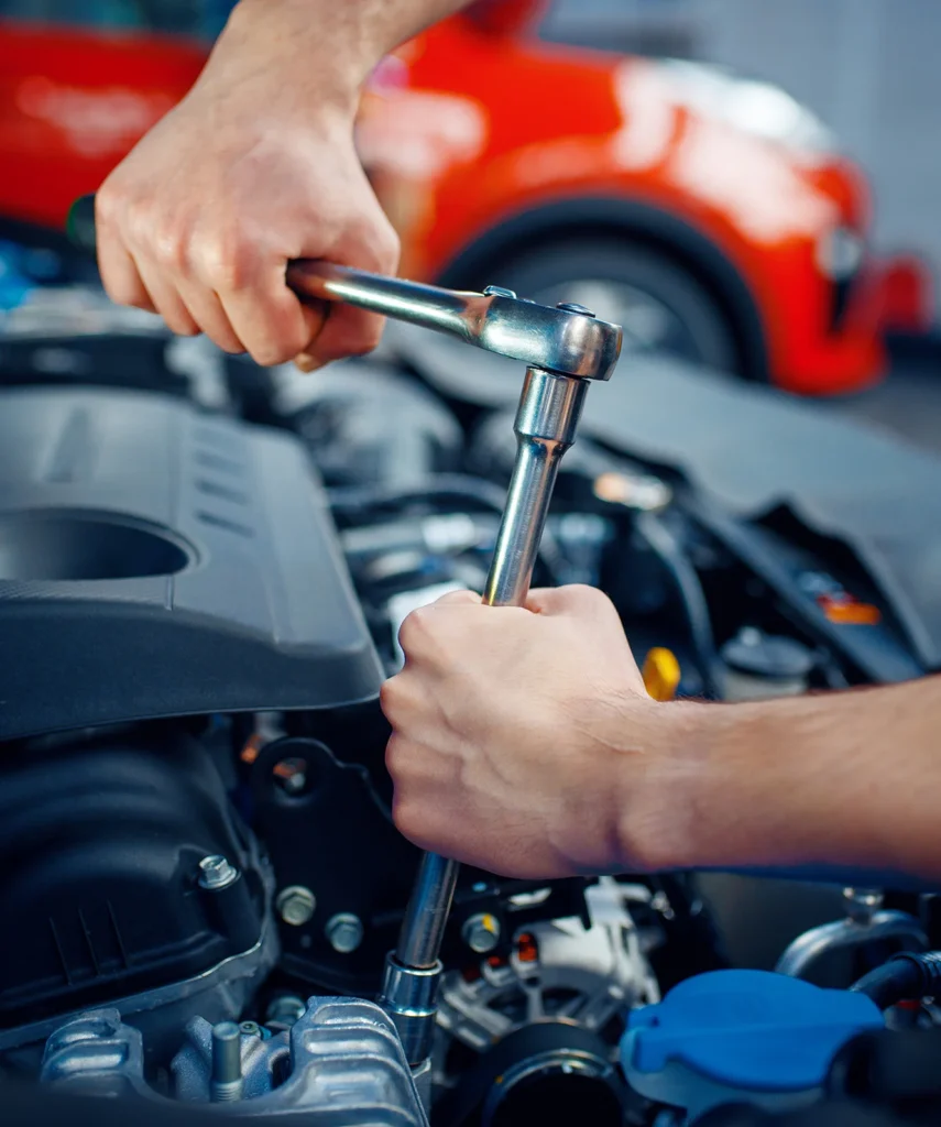 a car's engine getting worked on by a worker with a spanner.