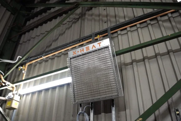 x-heat nano-heat heater mounted on a grey metal wall, the image is taken from a high angle.