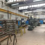 a warehouse with benshes going down the lefthand side, above the benches on the wall there is some x-heat heaters.